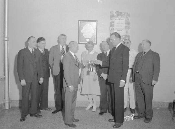 Ralph Runge, Local #1 Chairman of the WSDA membership committee, presenting the President Zander Membership Cup to Jay D. Ferguson, Chairman of the winning membership team of the Mendota State Hospital Local #13 at Mendota State Hospital. Also shown are team members,left to right: Louis Foss, Henry Carter, Gilman Hill, Jay Ferguson, Miss Metcalfe, Fred Mundon, Ralph Runge, L.V. Boyer,and Clarence Cole. The cup was awarded to the local showing the greatest increase in membership on a percentage basis during the months of November and December, 1943, taking into consideration the number of new members and reinstatements secured and the potential membership of the local.