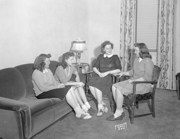 Four girls sitting in the parlor of Marshall Hall at Edgewood High School, 1000 Edgewood Avenue, for a committee meeting.