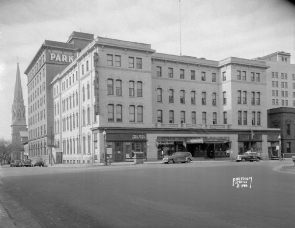 Park Hotel, 22 South Carroll Street, taken from West Main Street, with Liquor Shop, Wellentin & Son, Jewelers, Choles Floral Company, Madison Business Association, The Park Hotel Barber Shop. In the view is the rear of the Loraine Hotel, 119-125 West Washington Avenue, St. Raphael's Cathedral, 216 West Main Street, and the St. Nicholas Restaurant, 118 West Main Street.