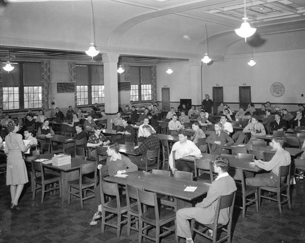 Senior male students taking ASTP examination in West High School Cafeteria, Ash and Regent Streets. ASTP was the Army Specialized Training Program to train men in specialized areas for service in the army. Soldiers were required to make at least a 110 or better on a special test for college aptitude.
