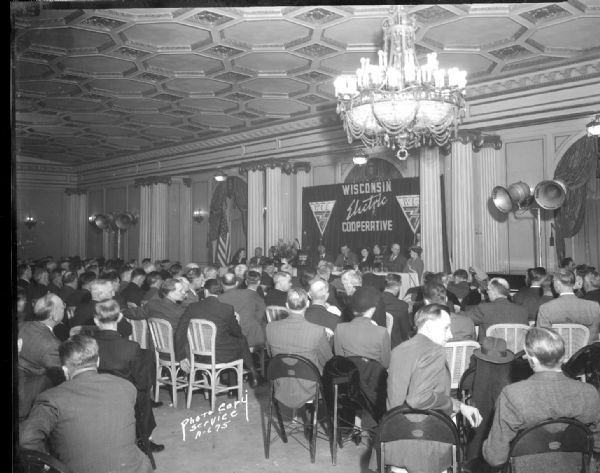 View from back towards the stage of Wisconsin Electric Cooperative delegates, from REA (Rural Electrification Administration) member cooperatives, attending the eighth annual state-wide meeting in the Crystal Ballroom of the Loraine Hotel. Taken for Harvey Schermerhorn, editor of Wisconsin REA News.