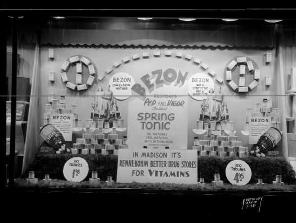 "Bezon" vitamin window display in the Rennebohm Drug Store #2, 204 State Street. One sign reads: "In Madison, it's Rennebohm's for Vitamins."