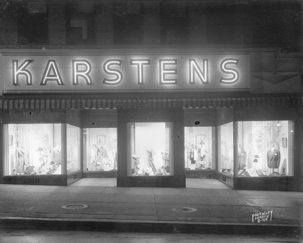 F.W. Karstens Company, 24 North Carroll Street, store front with display windows lit up at night.