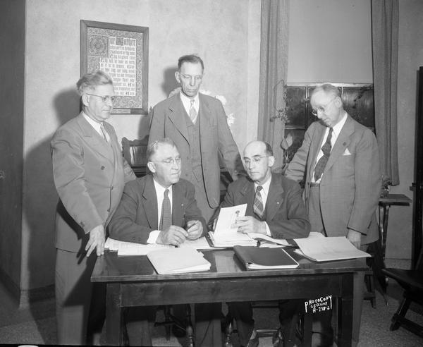 Group of five men around a desk at Methodist Hospital, 309 West Washington Avenue.