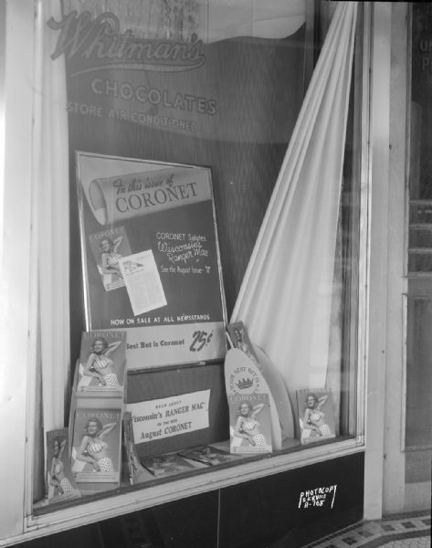 <i>Coronet</i> magazine display in the window of Rennebohm Drug Store #10, 676 State Street. "Read about Wisconson's Ranger Mac (WHA radio personality Wakelin McNeel) in the new August Coronet." A woman in a two piece bathing suit is featured on the magazine cover.