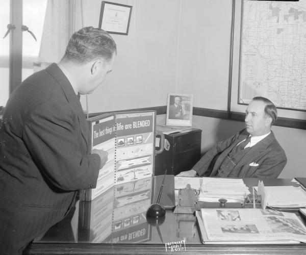 Mr. Rose showing Clyde S. Tutton a Lord Calvert whiskey educational display in the Wisconsin Treasury Department, Beverage and Cigarette Tax Division office. "The best things in life are BLENDED." Mr. Rose is head of the Division.