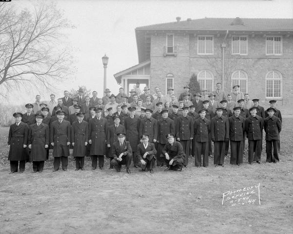 Group portrait of officer and civilian instructors of the U.S. Naval Training School (Radio) on the University of Wisconsin-Madison campus. Second man on left in front row is Elmer C. Zindars.