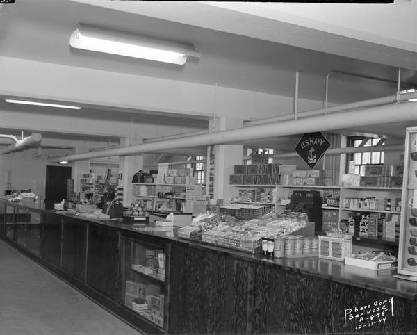 Interior view of U.S. Navy Ship Service Store with merchandise display on counter and shelves.