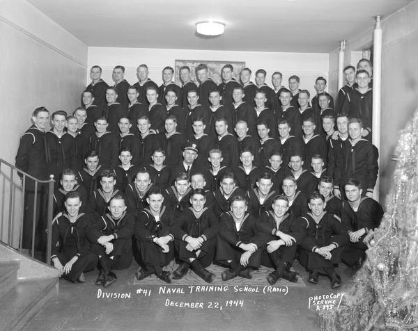 Group portrait of U.S. Naval Training School (Radio), Division #41, trainees, University of Wisconsin-Madison, with Christmas tree in the foreground.