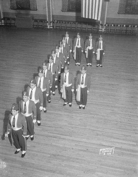 Elevated view of Fraternal Order of Eagles drill team in costume forming the letter "F" in an auditorium.