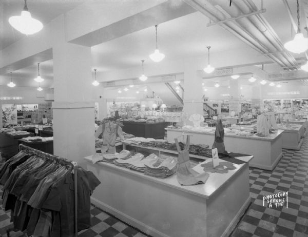 Wide angle view of clothing, shoes, luggage, electric appliances, and glassware for sale in Manchester's, Inc., basement.