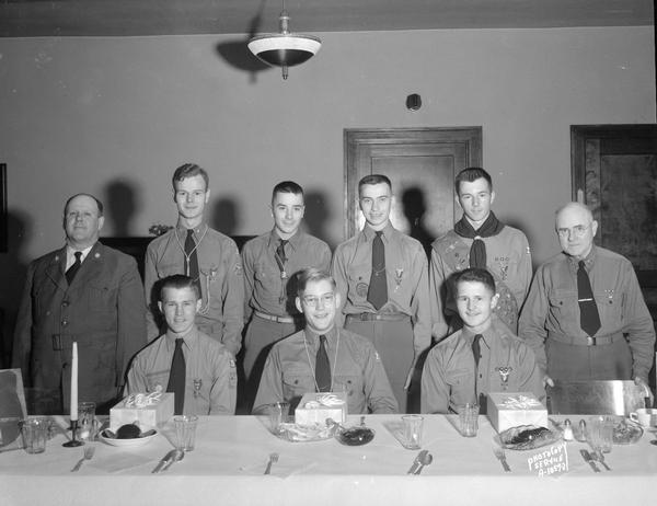 Boy Scouts, Troop #20 Explorer Patrol, from Christ Presbyterian Church, at farewell dinner for Olson, Roesen, and Hines, who were entering military service, sitting at a dinner table with four other scouts and a troop leader standing behind.