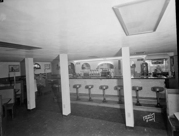 Ice Cream Bar interior, on Milwaukee Street, showing fountain, and booths along the all on the left, with several people sitting.