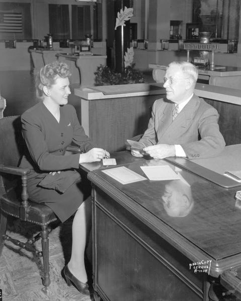 Harriet Peterson of the State Bureau of Probation and Parole opening a savings account with J. Edward O'Connell, manager of the Savings Department of the First National Bank, 1 South Pinckney Street.