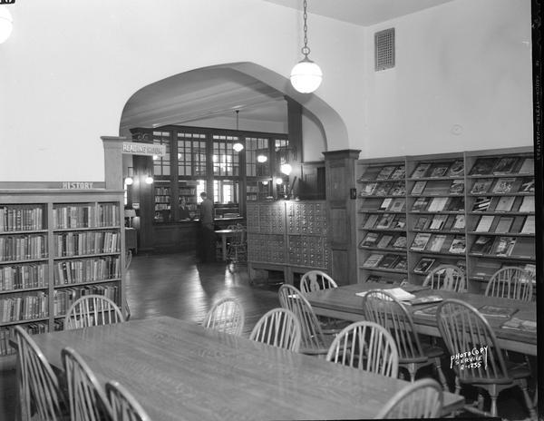 Interior of Madison Public Library, 206 North Carroll Street, showing Reading Room, magazine display shelves and history book section.