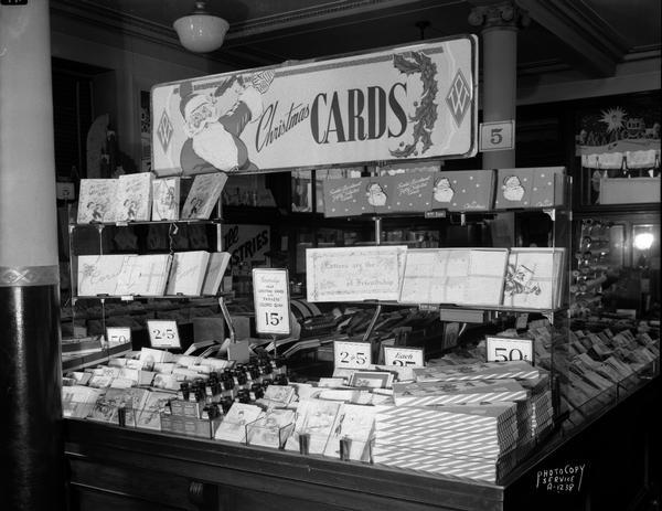 Christmas card display at F.W. Woolworth Co,, 1 East Main Street, with sign that reads: "Personalize your Christmas cards with Parker's Colored Quink." There is an image of Santa Claus on a sign. Taken for Parker Pen Company.