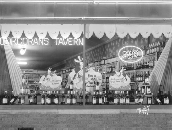 Display window at Cocoran's Tavern, 2605 University Avenue, featuring rabbits holding bottles of Roma wine "for your Easter dinner."