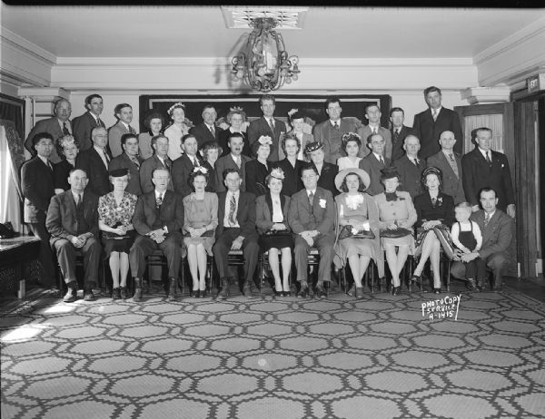 Group portrait of Modern Woodmen of America Insurance Camp #365, with men and women and one child. Taken in the Colonial Room at the Hotel Loraine.