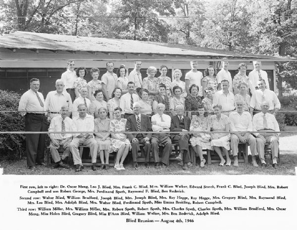 Group portrait of family members at the Blied family reunion at the Blied cottage. Contains all the names of those present.