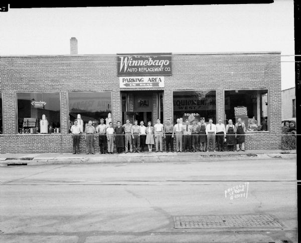 19 employees (entire sales force) standing in front of Winnebago Auto Parts Replacement Parts Company, 103 North Park Street.