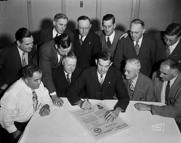 American Federation of State, County & Municipal Employees executive board witnessing the signing of a charter for the Atlantic City, New Jersey convention hall ushers union by Arnold S. Zander, general president. Front row left to right: vice presidents Michael Moro (seated), William McEntee and Jerry Olrich (both standing), Elling Munkeby, President Zander, International secretary-treasurer H.Z. Collier, and vice president George Thorpe. Back row left to right: vice presidents John Leary, William Darraugh, William Boeger, William B. Honea, and Raymond Knott.