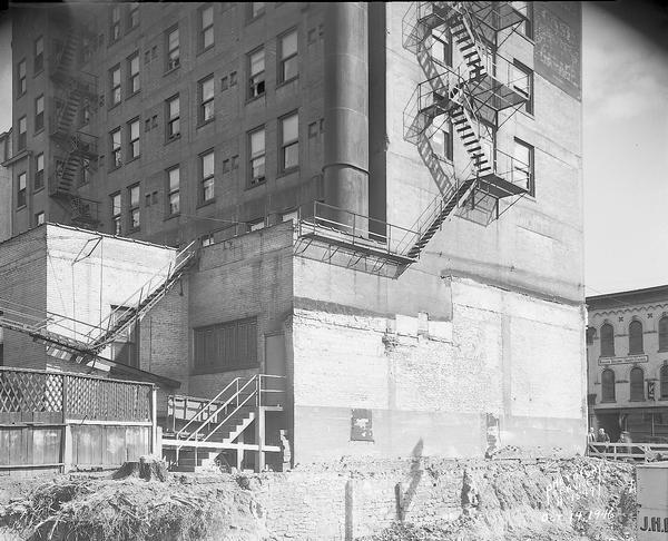 Wisconsin Telephone Company construction site at rear of Park Hotel taken from southwest showing rear of the hotel and the 115 West Main Street building with Kyser Co. tailors, Service Grocery and Madison Building & Construction Trades Council.