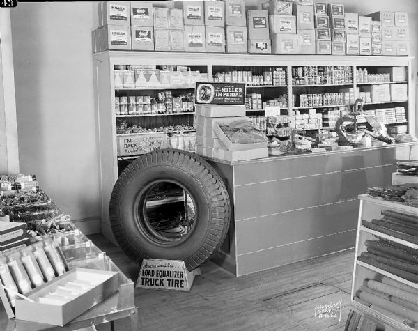 Interior of Holmes Tire and Supply Company, 431 West Main Street. View from the rear showing a large truck tire near a display.