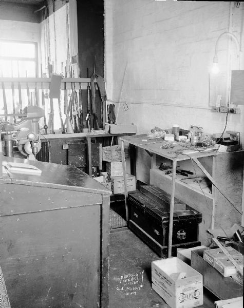 Interior of Four Lakes Sports Company at 2441 East Washington Avenue. Shows part of office, workshop, and gun rack with guns, in relation to open stairway. Taken for Continental Casualty Company.