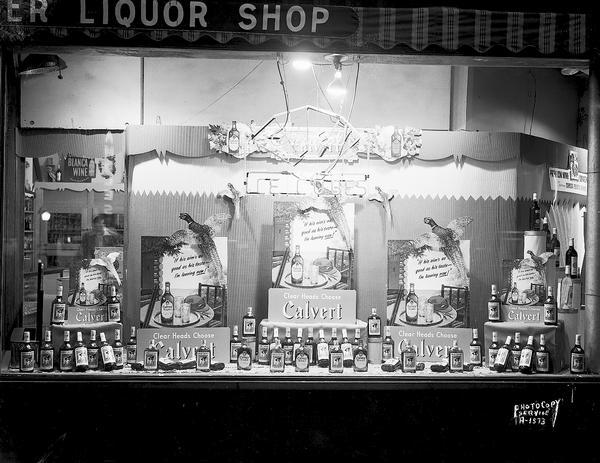 Display window at Badger Liquor Store, 402 State Street, showing Calvert Liquor, with sign picturing pheasant and gun and the words "If his aim's as good as his taste, I'm leaving now." Also, "Clear heads choose Calvert."