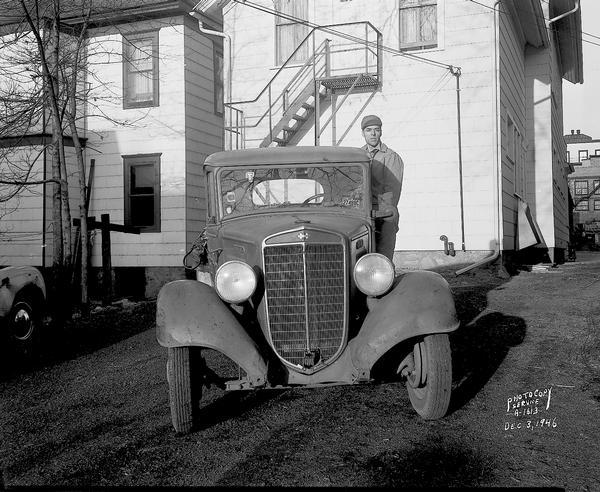 Front view of a Conklin & Sons International pickup truck. There is a man standing on the running board.