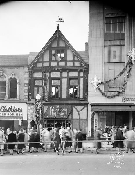 Heidelberg Hofbrau Restaurant, exterior view, with crowds of people looking at aftermath of a fire, 20 West Mifflin Street. Also shows The Hub, a mens' clothing store, 22 West Mifflin Street, and Baron Brothers Department Store, 14 West Mifflin Street.
