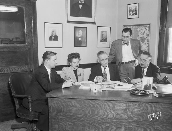 CUNA (Credit Union National Association) <I>Bridge Magazine</I> executive group. There are four men and one woman at a desk looking at materials.