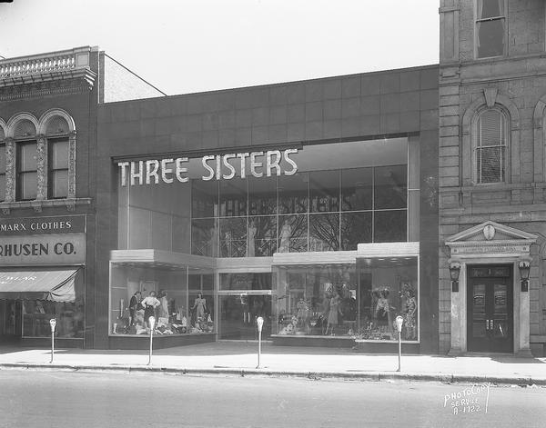 Three Sisters women's dress shop, 5 North Pinckney Street.  Also shows American Exchange Bank entrance, 1 North Pinckney Street, and Olson & Veerhusen Company men's clothing store, 7- 9 North Pinckney Street.