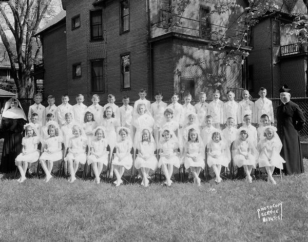 Group portrait of First Communion class, Holy Redeemer Catholic Church, with thirty-nine children, a nun and a priest.