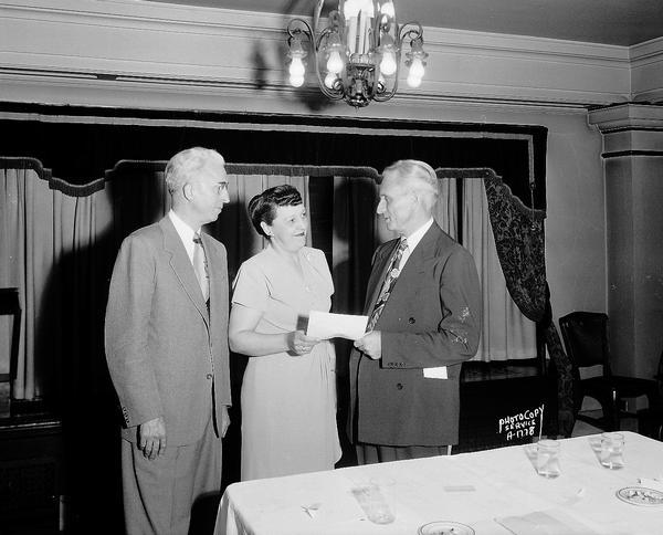 Presentation of certificate, American Federation of Laundry Workers International Union, with two men and one woman, taken in the Colonial Room at the Hotel Loraine, 123 West Washington Avenue.