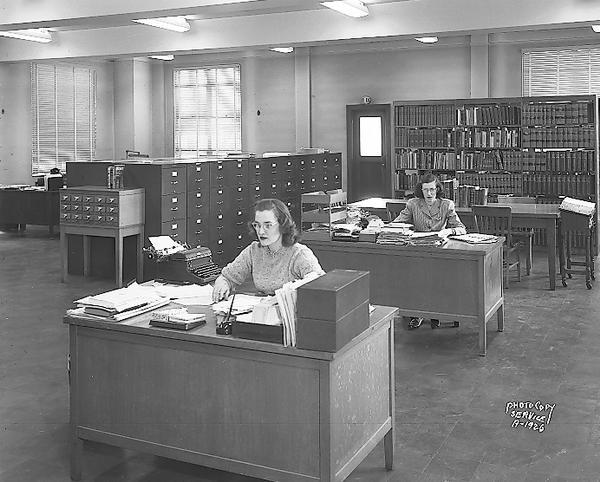 Library in the American Federation of State, County and Municipal Employees Building, 448 West Washington Avenue. Also shows two women clerks sitting at desks.