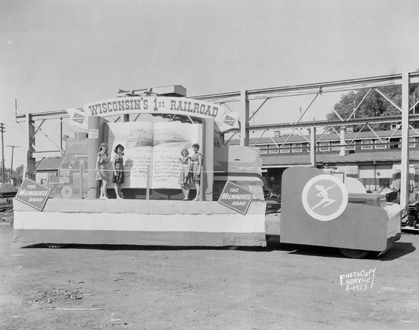 The Milwaukee Road float for Wisconsin Centennial Parade, "Wisconsin's First Railroad," with four women in sun dresses.