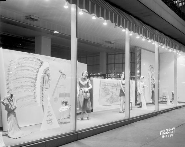 Manchester's Incorporated, 2 East Mifflin Street, "Petti" sun dresses display window, "Petite sun separates, and Indianhead fabric." Behind the mannequins are two large posters of Native Americans.