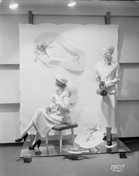 A foyer display at Manchester's, Inc., 2 East Mifflin Street, featuring two mannequins wearing yellow dresses. A sign reads: "If you like yellow, you are a true friend and can keep secrets."