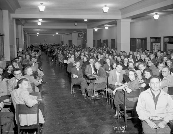 A large group of Ohio Chemical and Surgical Equipment Company employees sitting at tables playing bingo at East High School, 2222 East Washington Avenue.