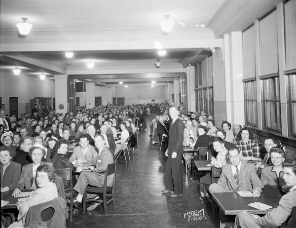 A large group of Ohio Chemical and Surgical Equipment Company employees sitting at tables playing bingo at East High School, 2222 East Washington Avenue, alternate view.