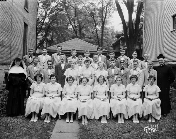 Group portrait of the graduating class of Holy Redeemer Catholic Church School, 128 West Johnson Street, including  thirty graduates, a priest and a nun.