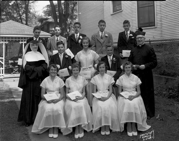 Group portrait of seven boys and five girls with one nun and one priest, Holy Redeemer Catholic School, 128 West Johnson Street, eighth graduation class.