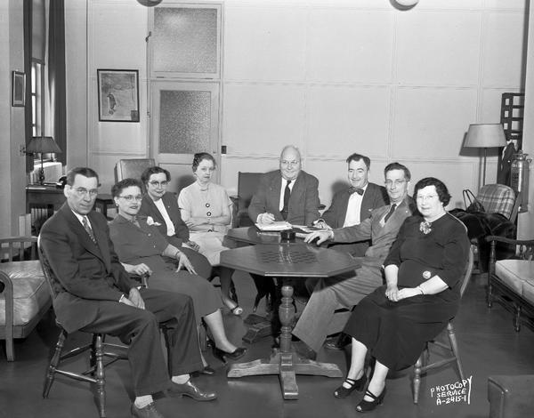 Group portrait of officers of the employee club sitting around game tables in the Pioneer Room at the Wisconsin Telephone Company, 122 West Main Street.