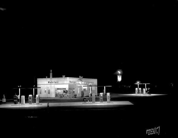 Night view of Robert Blossom's Mobil gas station, 3702 East Washington Avenue and Highway 51. Background includes Club LaMark.