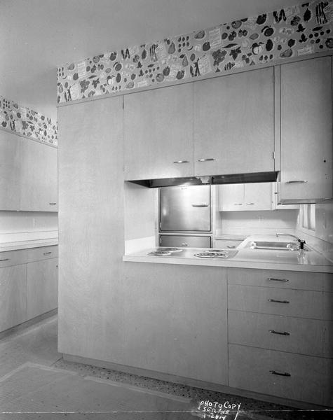 Kitchen at 614 Odell Street(?), taken for 1955 Parade of Homes, looking through opening in cabinet wall to show stove, sink and refrigerator, Revco and Preway equipment, taken for Graybar Electric Company.
