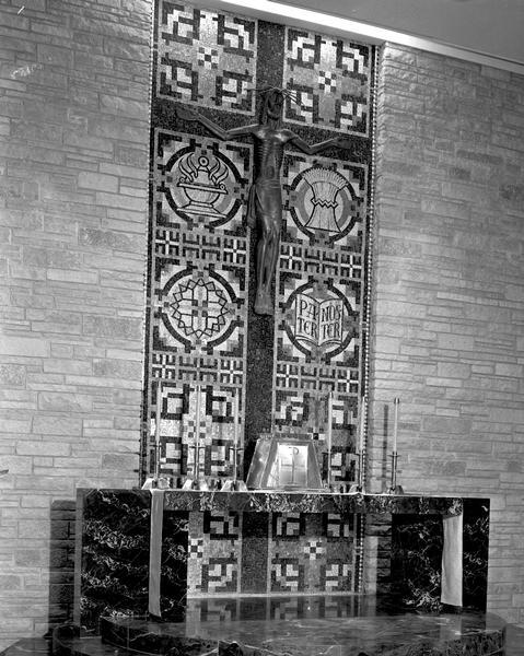 Bronze crucifix, wall mosaic of religious symbols, and altar in St. Mary of the Lake Catholic Church, 5460 Mary Lake Road.