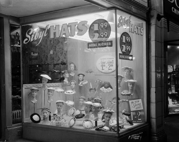 Sibyl Hats, 119 West Mifflin Street, with an exterior view of the right hand window with a display of hats and a sign that reads: "$1.99-$2.99, None Higher."