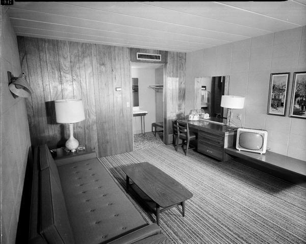 Interior view of a room at the Holiday Inn Motel, 4402 East Washington Avenue. View includes a day bed, a television, a table with a lamp, and a vanity with view into closet area.