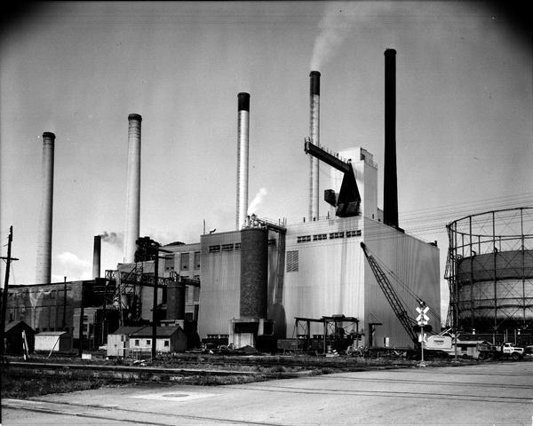 Exterior view of Madison Gas & Electric Company Blount Street electric power plant. View is across the railroad tracks and includes the power plant, smokestacks, a truck, and a crane.